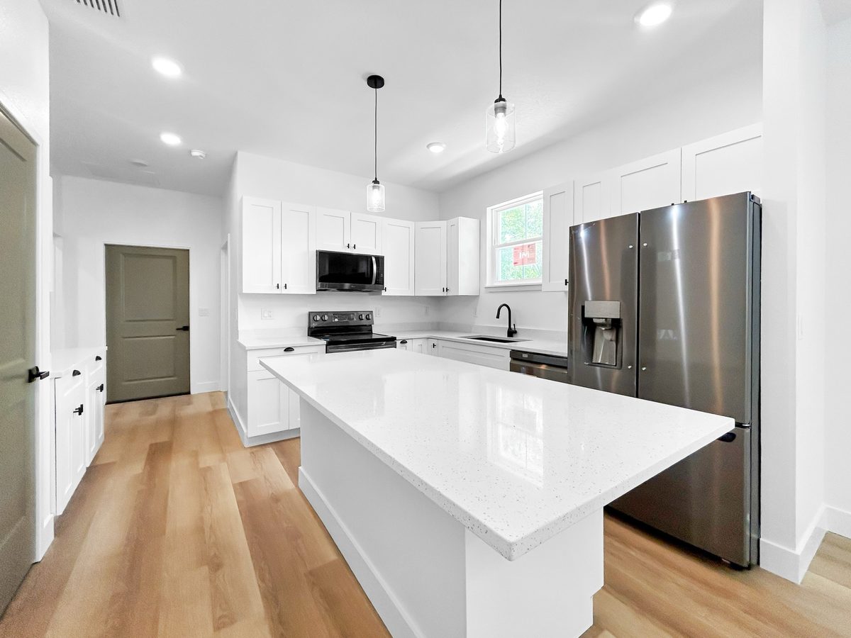 Kitchen at 1010 Hickory Avenue Sanford - white cabinets, solid surface island, stainless steel appliances, pendant lights