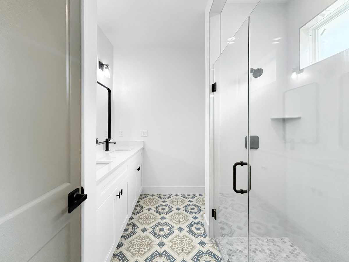 Bathroom at 1010 Hickory Avenue Sanford - patterned tile floor, glass walk-in shower, black fixtures